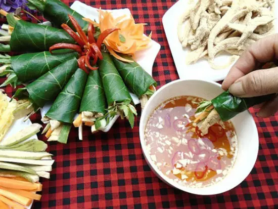 Bày nem tai thính ra đĩa, cuộn với lá sung, dưa chuột, cà rốt, dứa và chấm nước chấm chua cay
