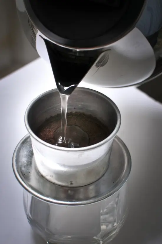 Cho nước vào phin để pha cà phê