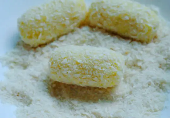 Lăn những miếng khoai tây bọc xúc xích qua bột chiên xù